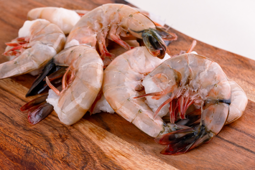 Raw shell-on jumbo shrimp arranged on a wooden board