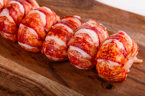 Fresh lobster tail meat arranged on a wooden board