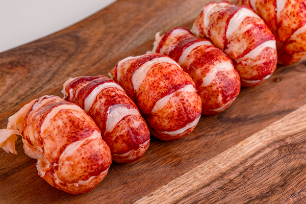 Fresh lobster tail meat arranged on a wooden board