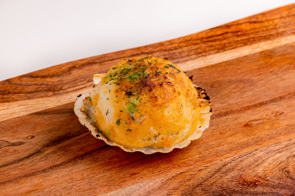Double stuffed seafood clam topped with herbs on a wooden board