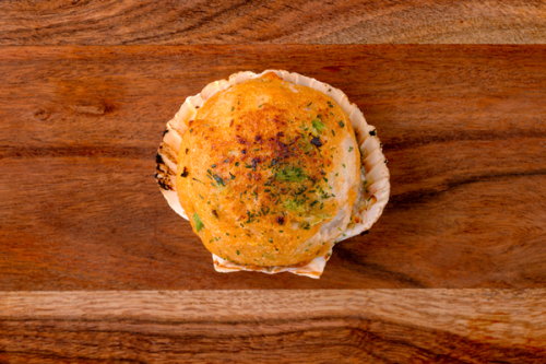 Double stuffed seafood clam topped with herbs on a wooden board