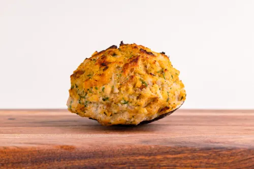 Double stuffed seafood clam topped with herbs on a wooden board